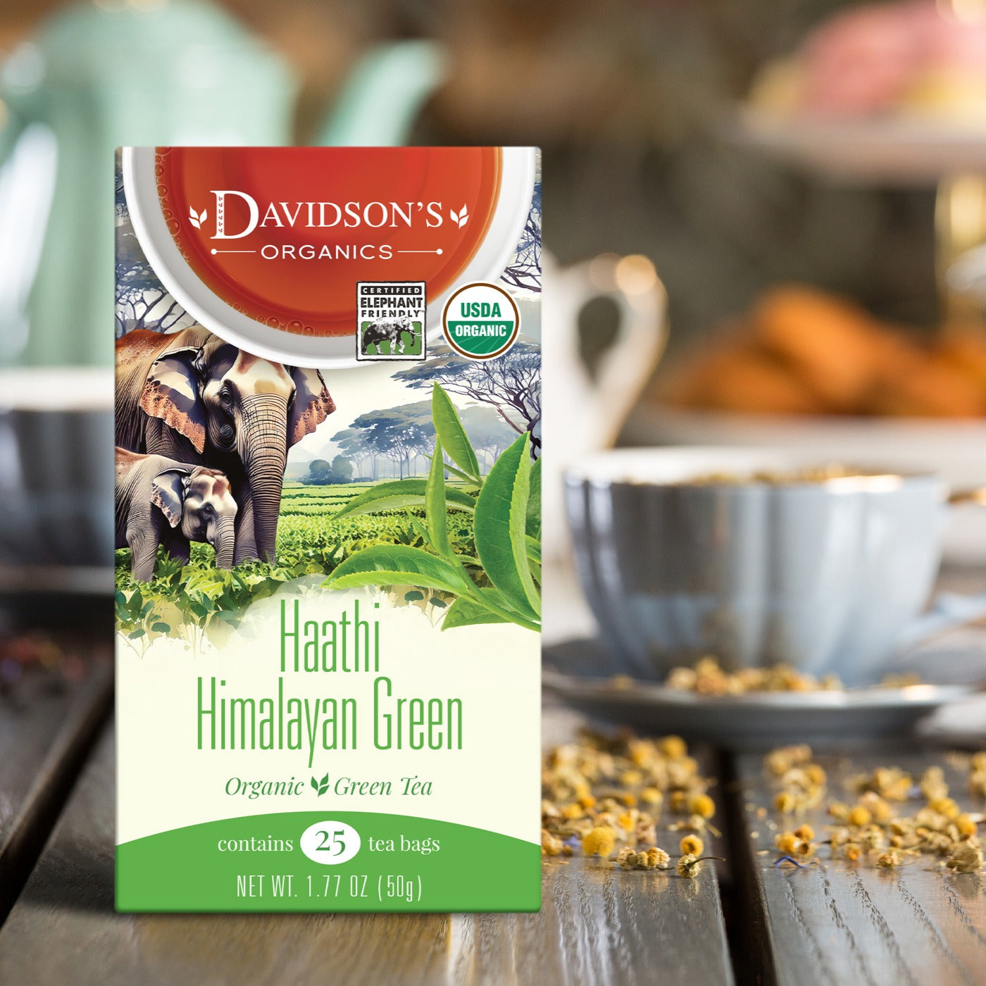 Box of Davidson's Organics Haathi Himalayan Green tea with a blurred background of a tea cup and leaves.