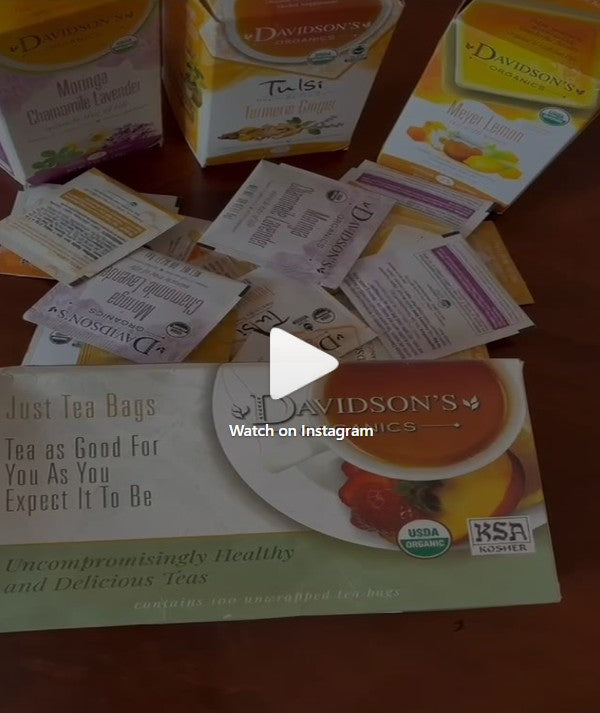 A collection of Davidsson's Organic tea bags and tea box packaging arranged on a wooden surface, with a central 'Watch on Instagram' overlay.